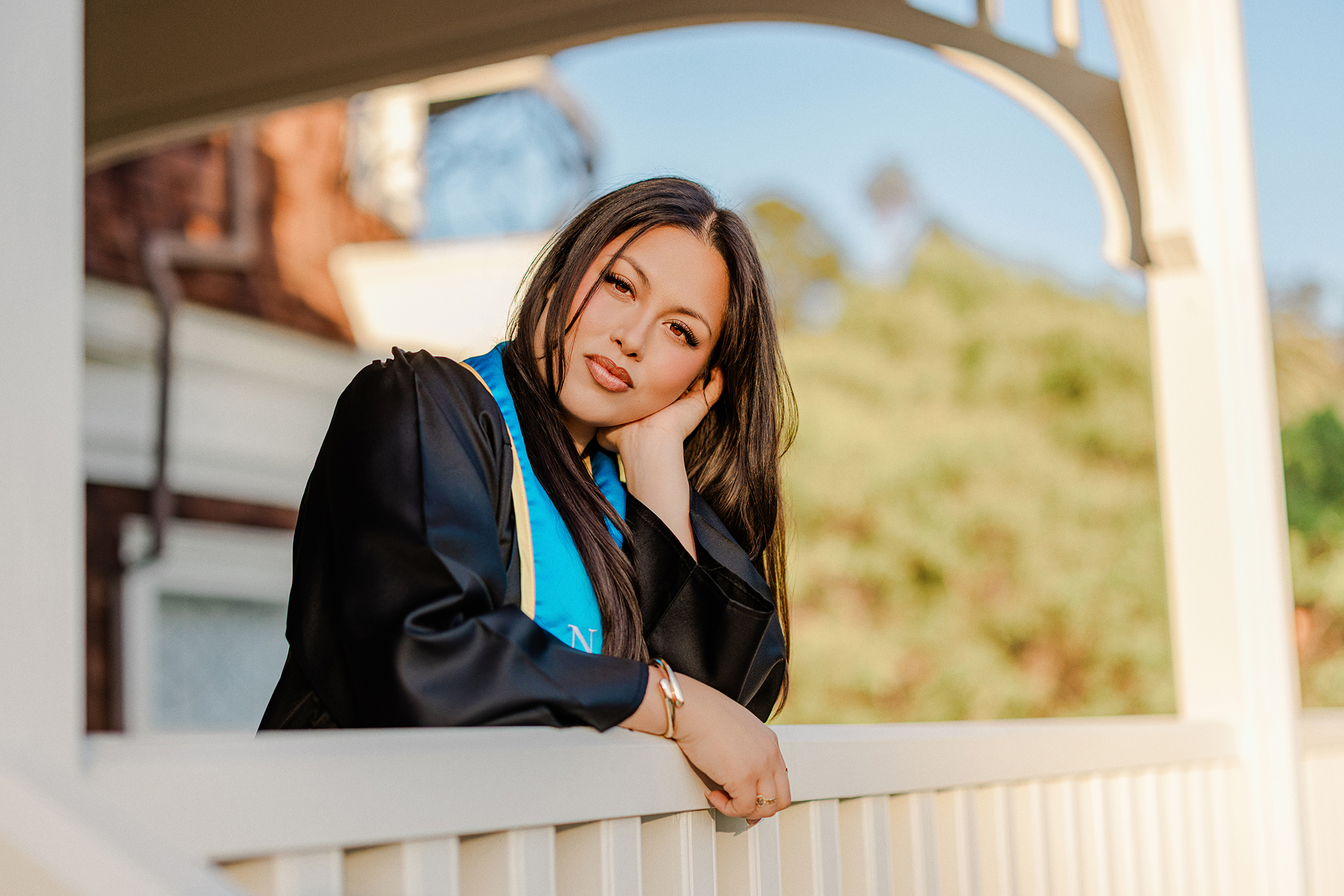 Dominican University nursing graduate posing beneath campus architecture in San Rafael