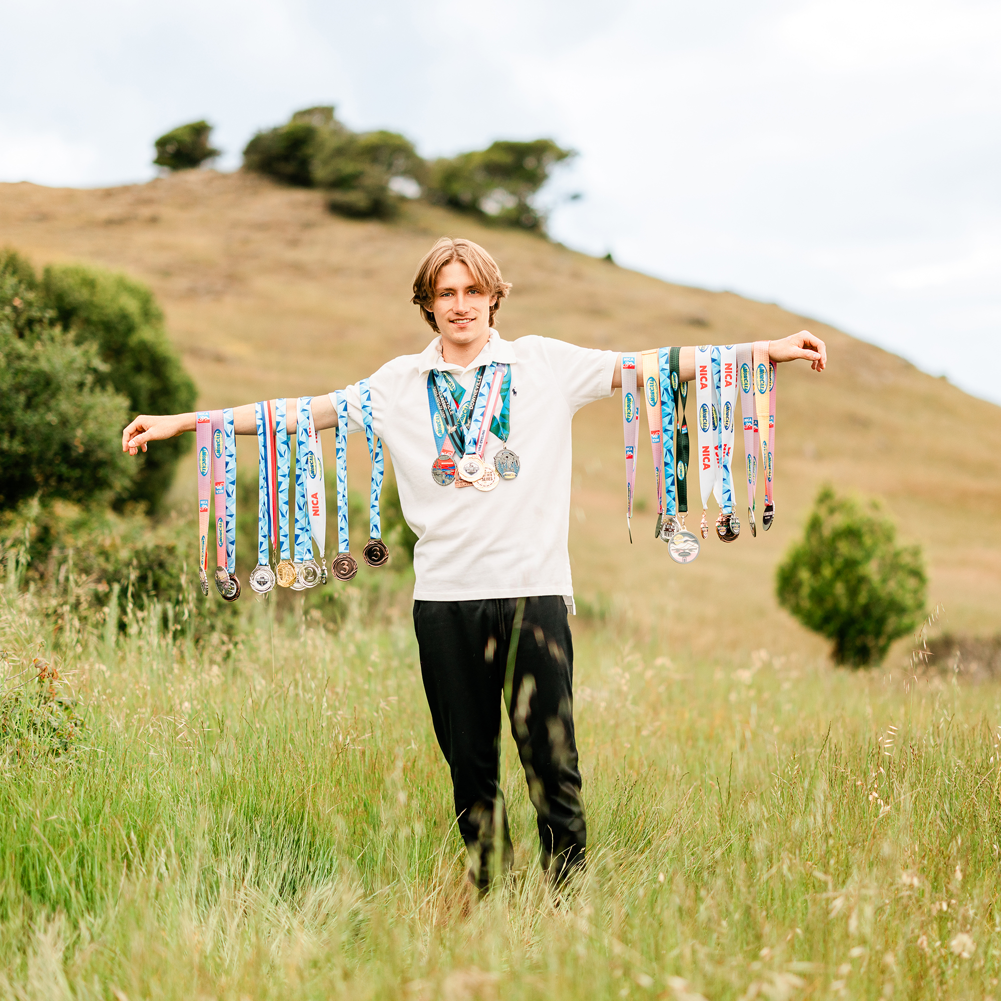 Redwood High School mountain biker displaying cycling medals during senior portrait session