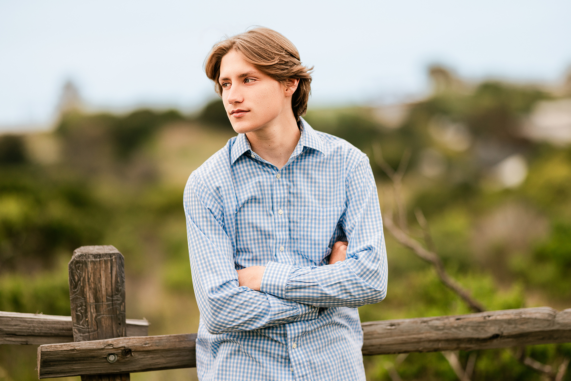 Redwood High School senior leaning against a rustic fence during an outdoor senior portrait session