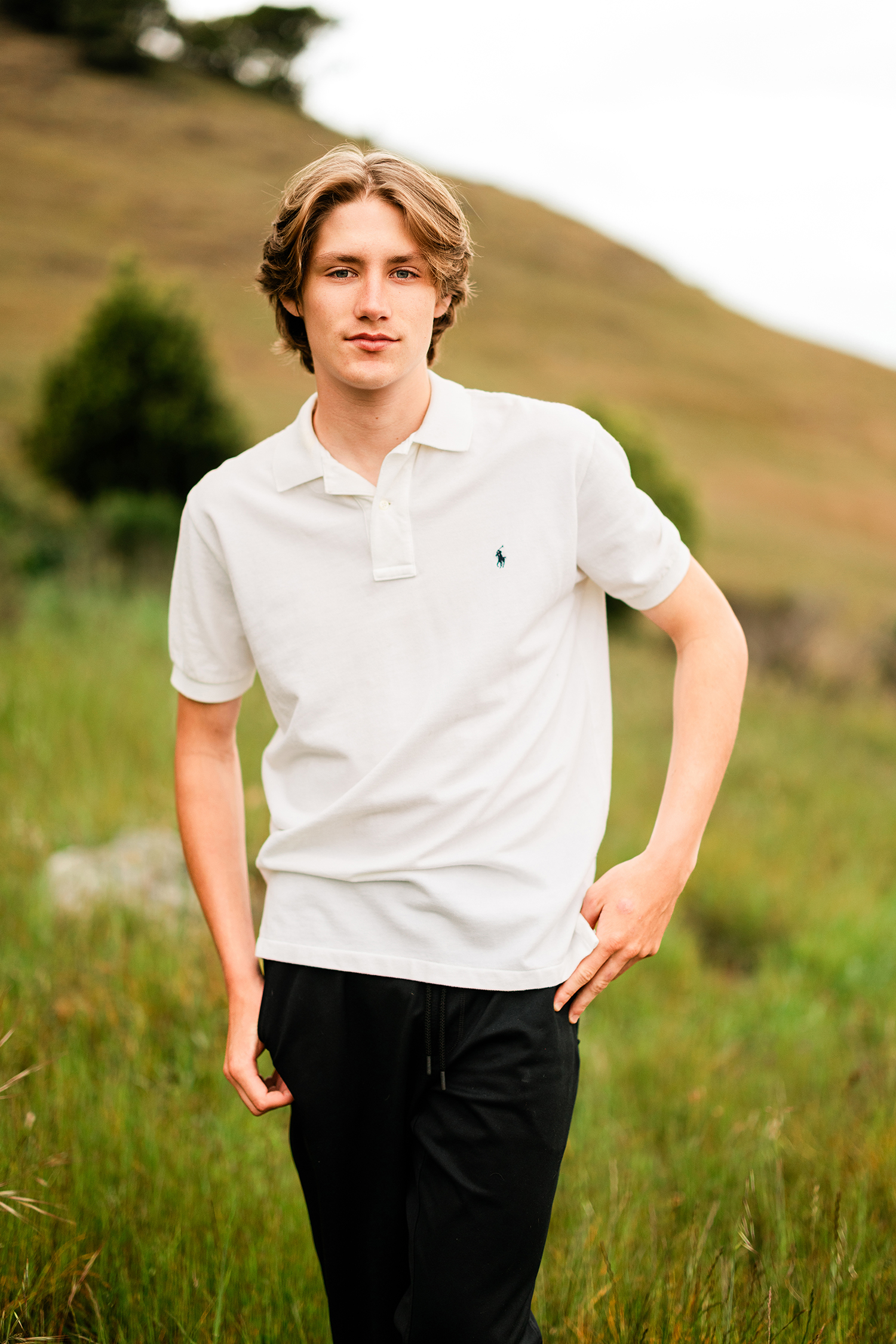 Redwood High School senior portrait in a white polo shirt with soft hillside background