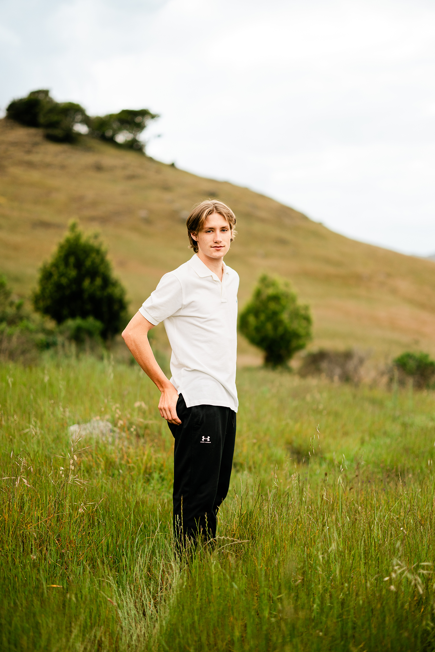 Redwood High School senior standing in a grassy hillside meadow during an outdoor senior portrait session in Marin County