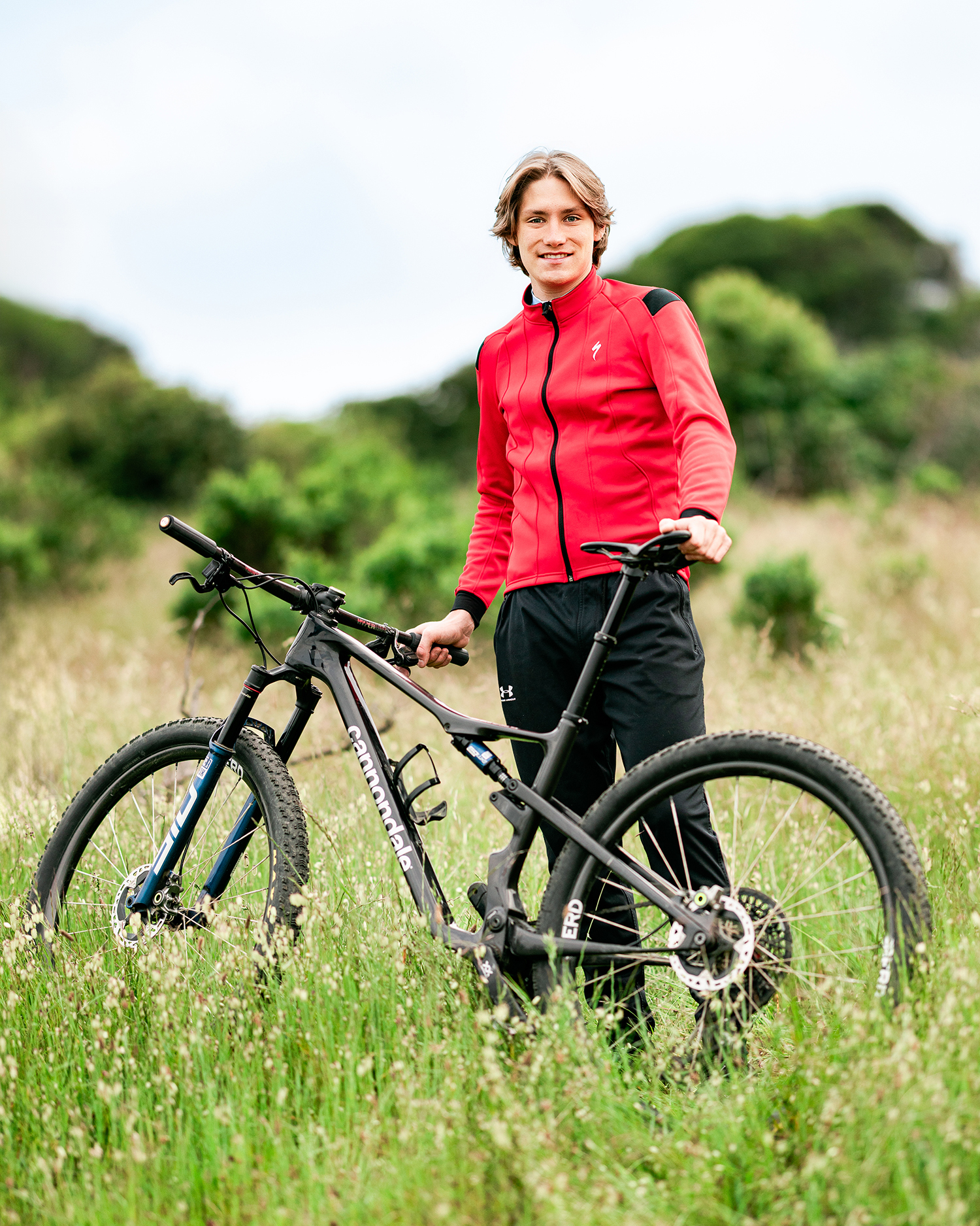 Redwood High School senior posing with his mountain bike in a grassy field in Marin County
