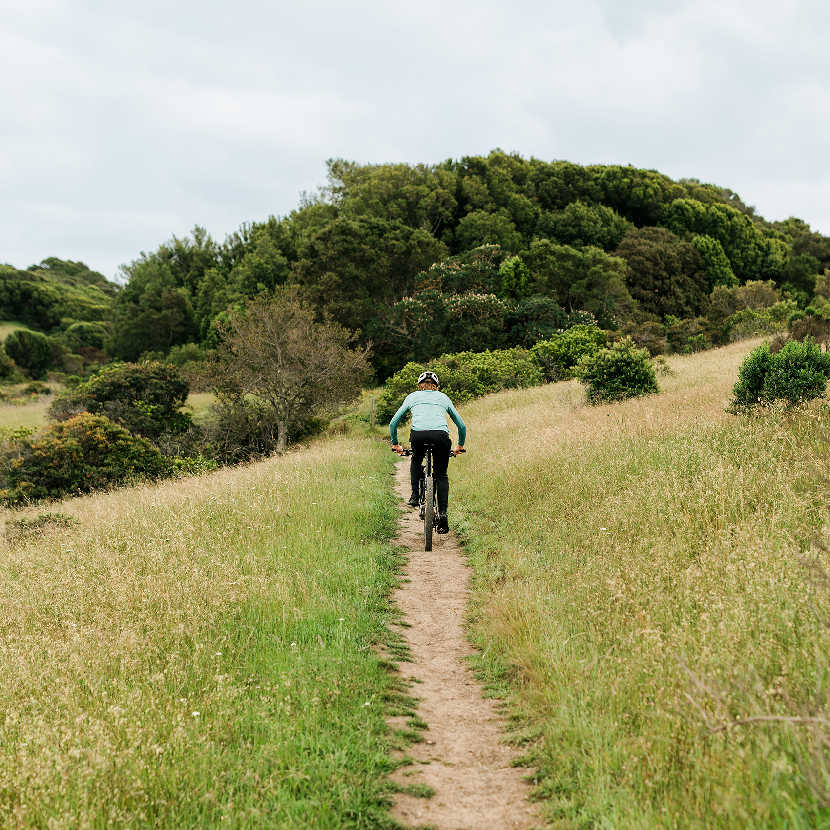 Redwood High School senior mountain biker riding along a singletrack trail through rolling Marin County grasslands